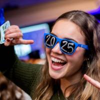 A grad smiles and points at her 2025 glasses